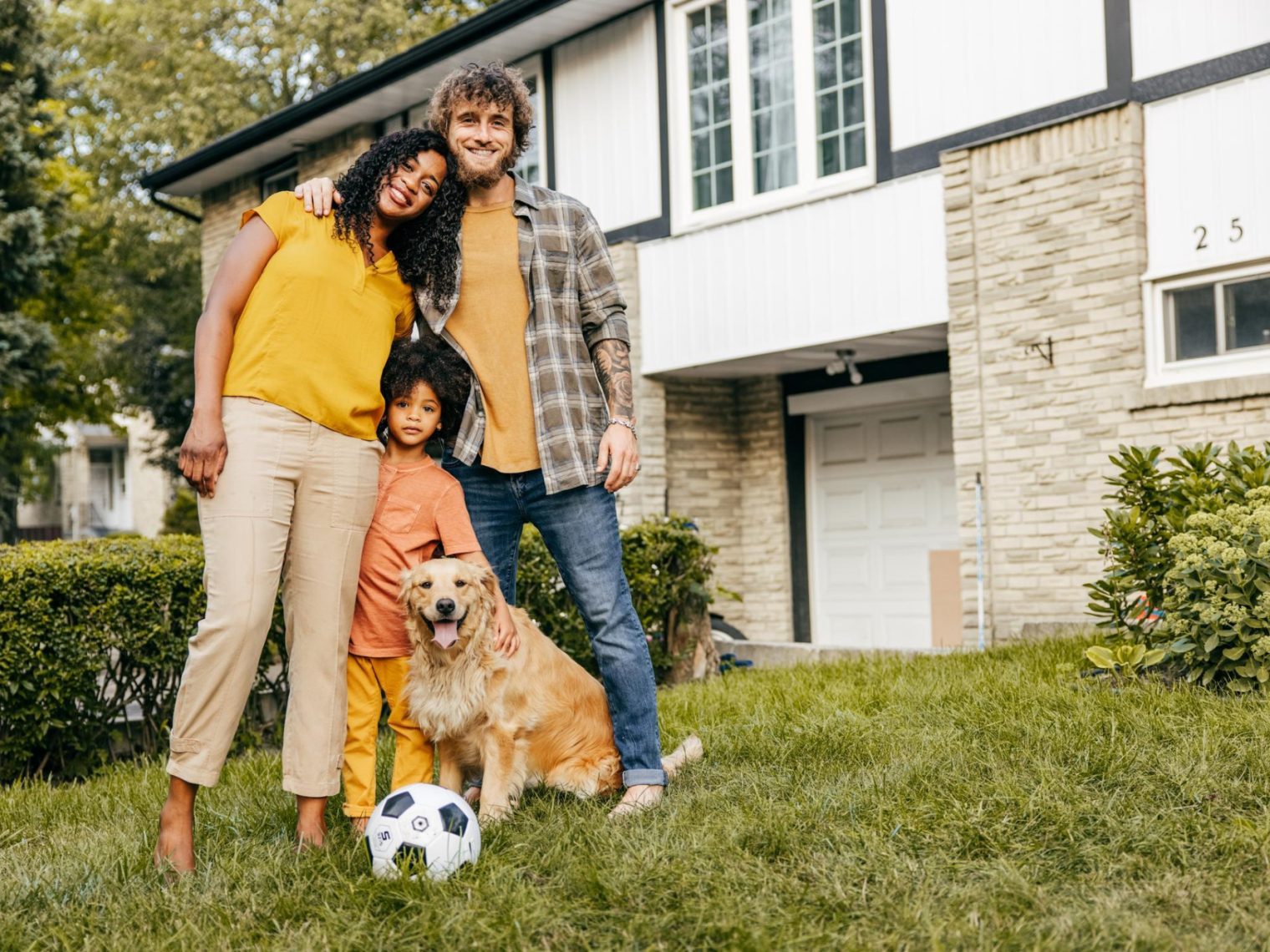Multi-ethnical family and their dog in front of their house.