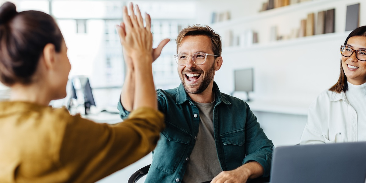 A man and woman high five to celebrate a success.